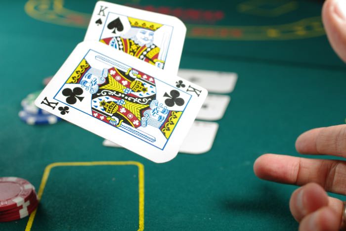 a photo of a poker table, a hand tossing two cards: both kings