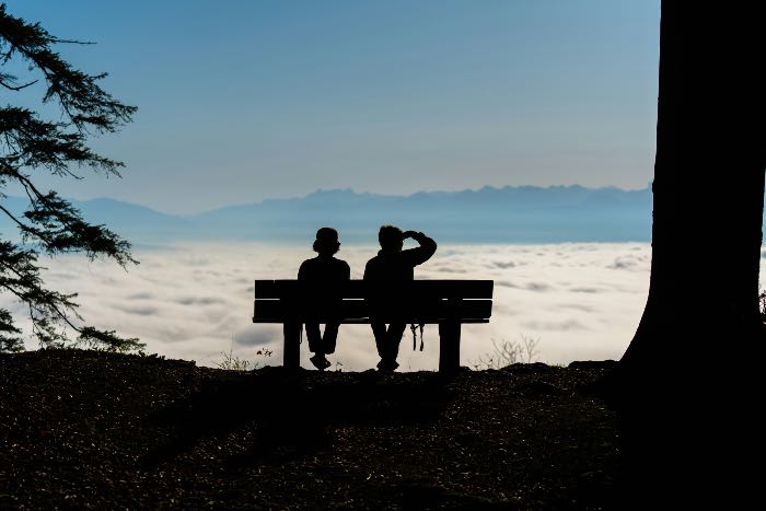 a photo from behind two people, sitting on a bench, the view in front of them is beautiful