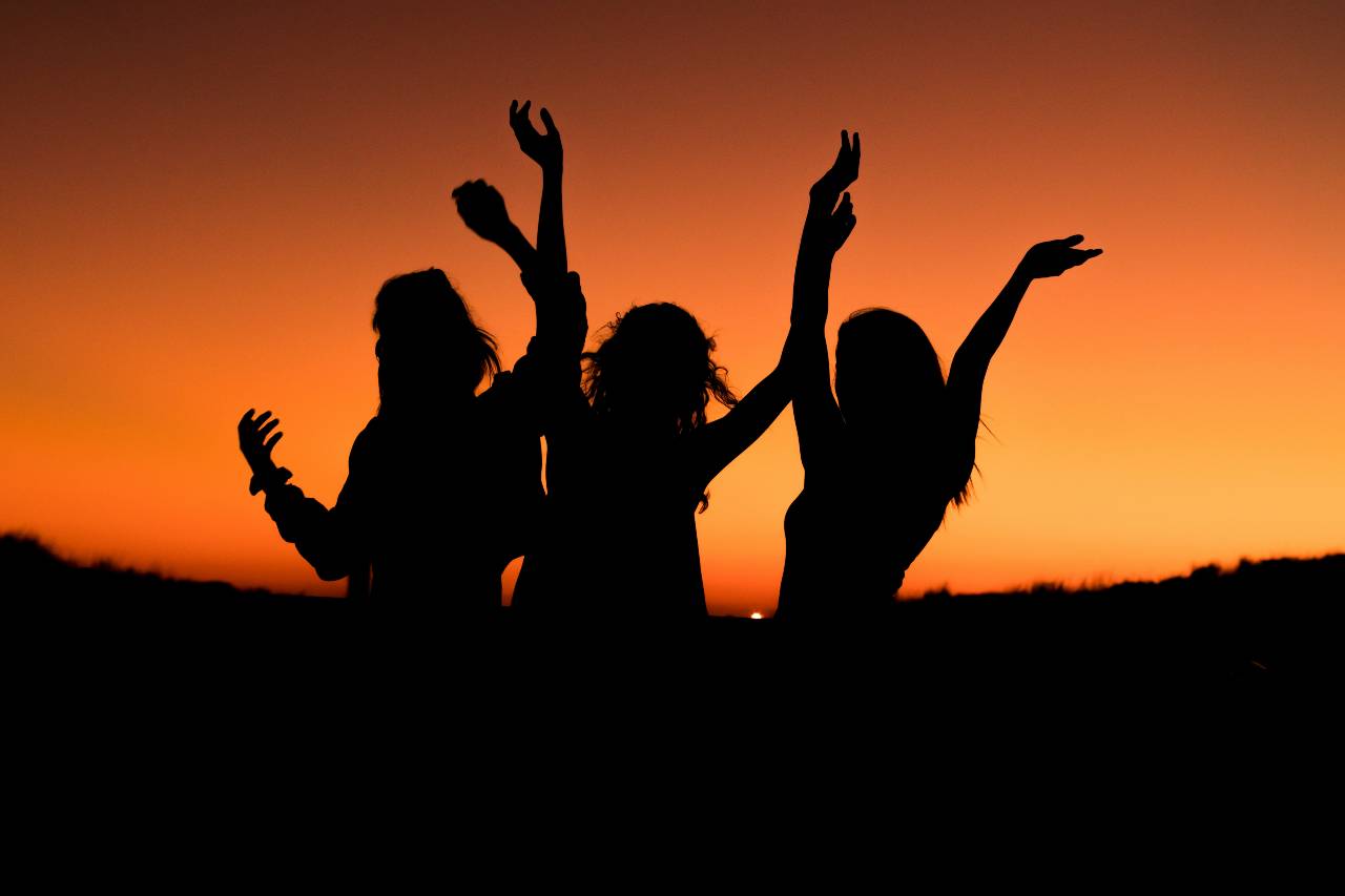 a photo of people in silhouette, arms raised