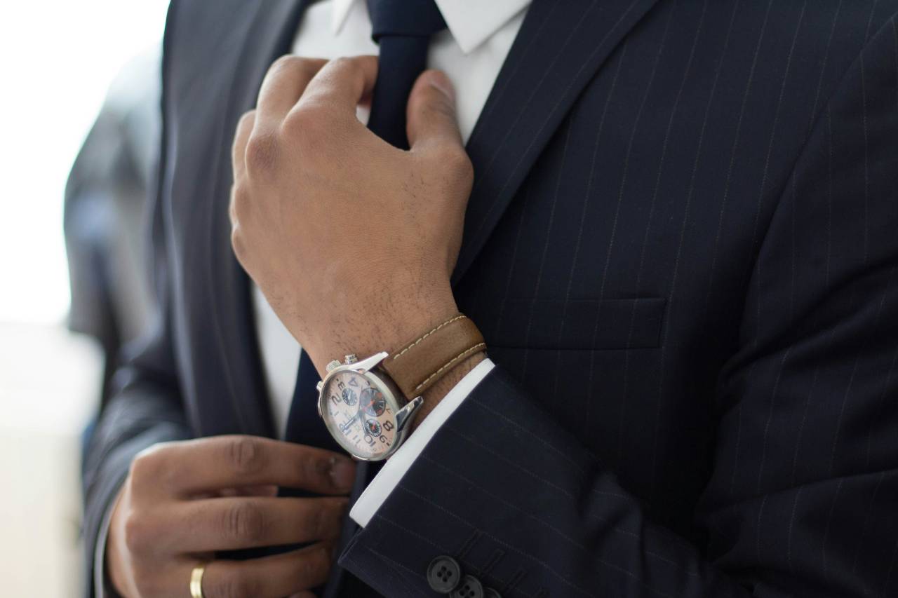 A photo of a person in a suit adjusting their tie.