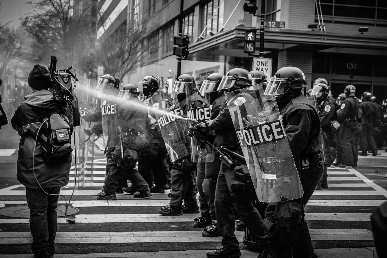 a photo of police advancing in riot gear, using water to disperse