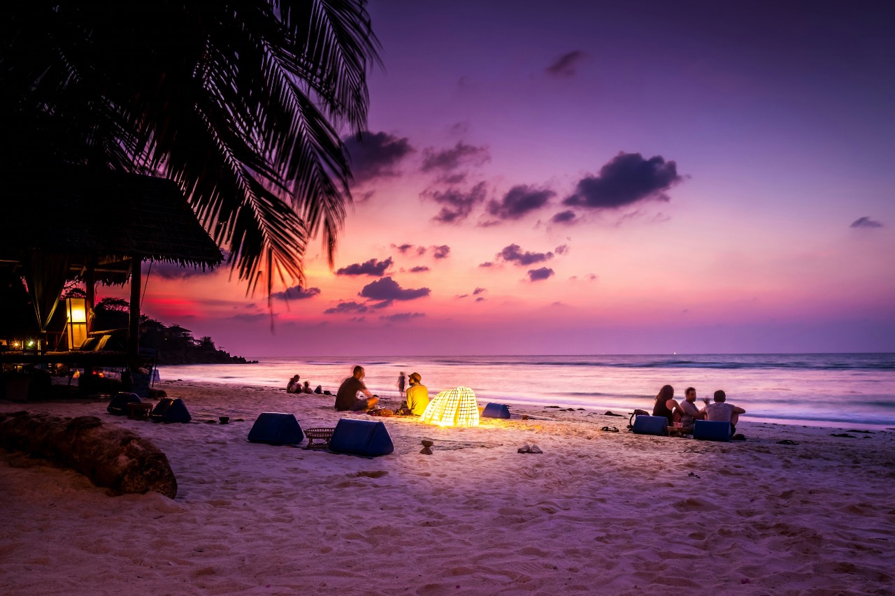 a photo of people gathered at a beach at late sunset