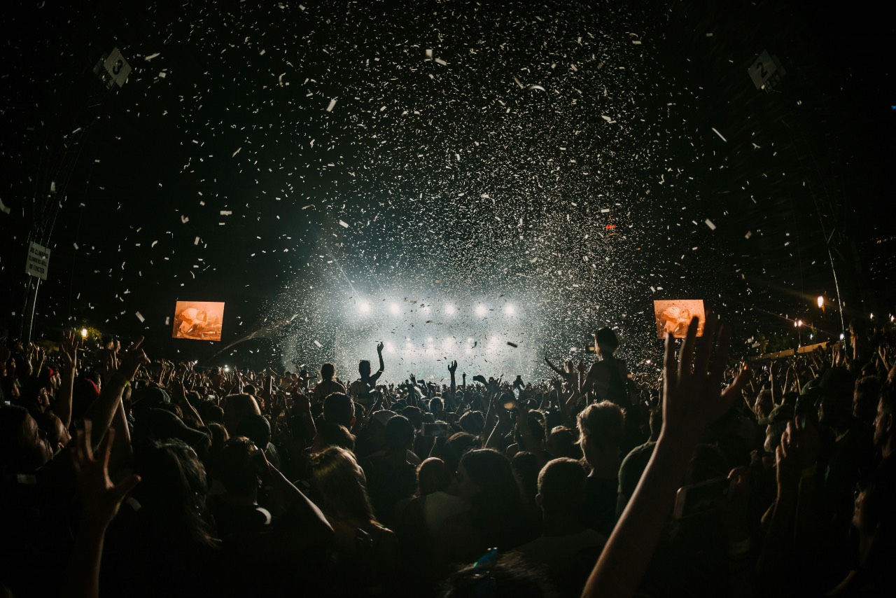 a photo of a concert, confetti in the air, white lights from the stage