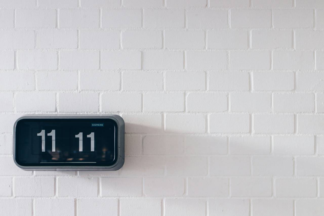 a photo of a white wall with a black clock on it, displaying "11:11"