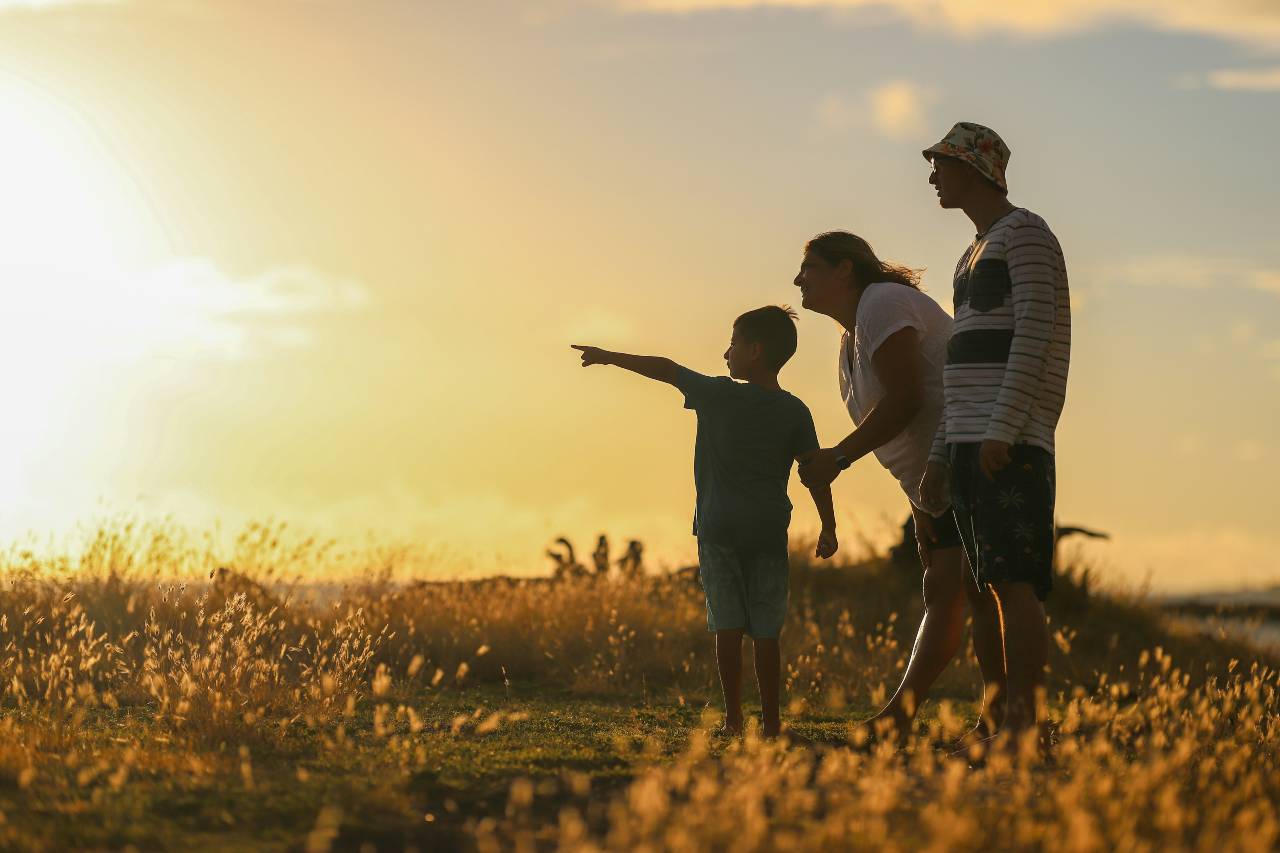 a photo of a young boy pointing while two adults look on