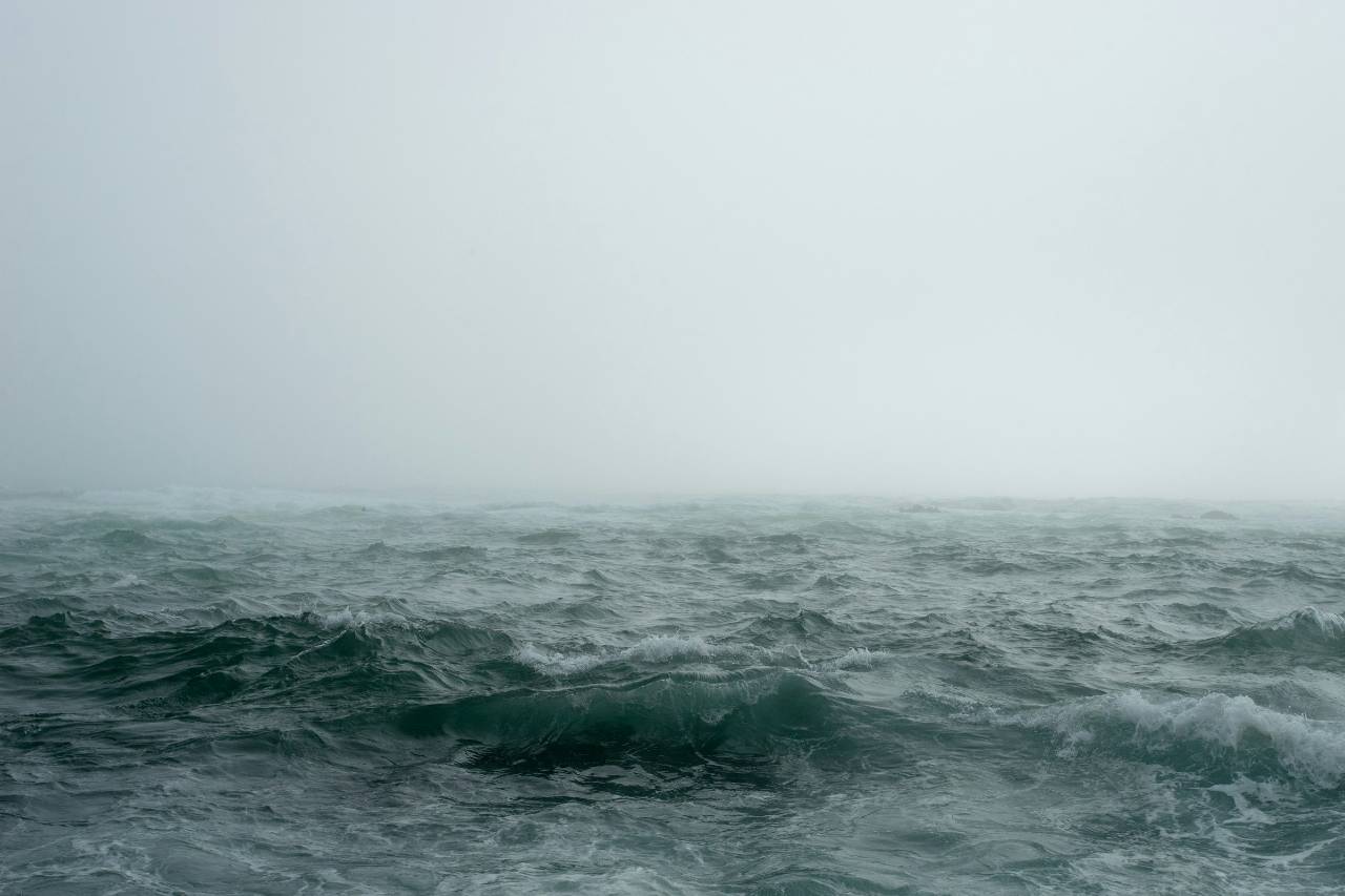 a photo of a foggy sea, waves picking up