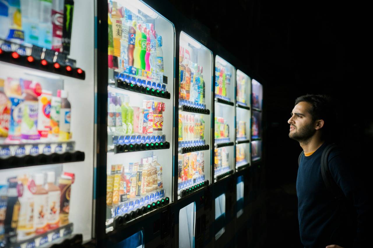 a photo of a person standing in front of a drink case contemplating what to pick