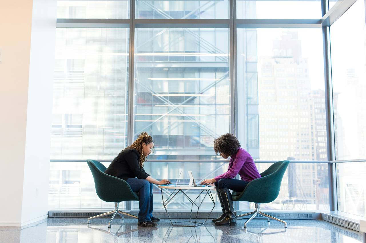 a photo of two people working in front of great glass windows