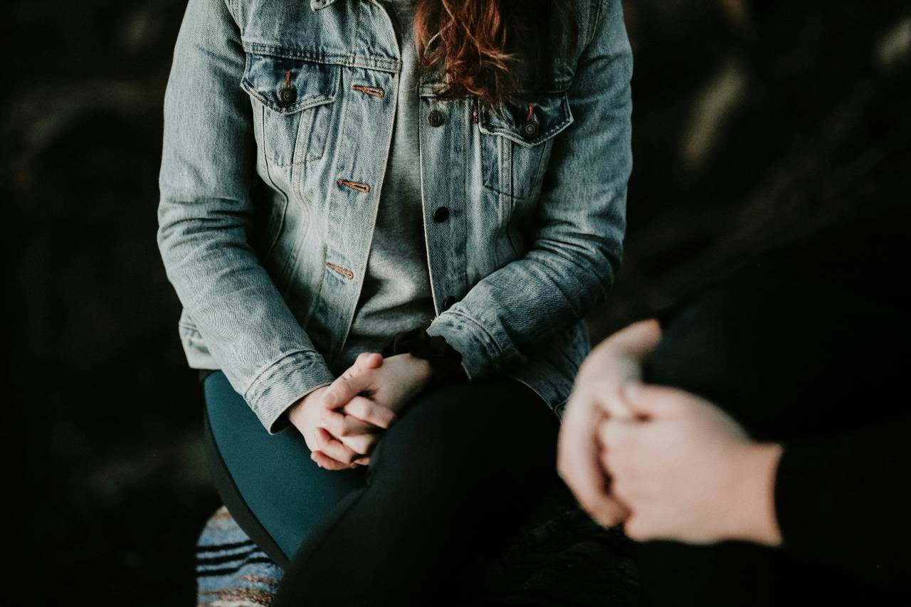 a photo of two people sitting, hands in laps.