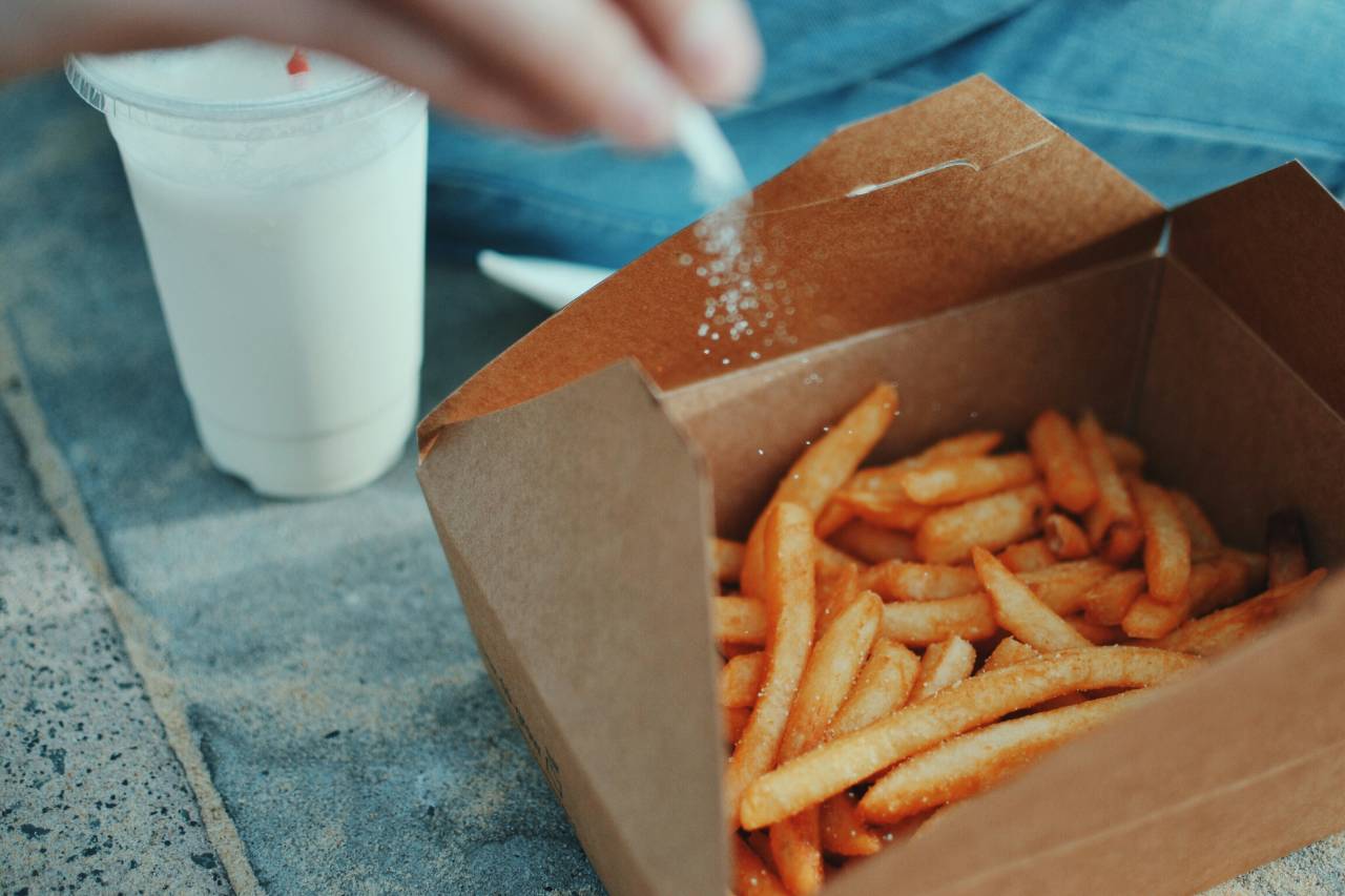 a photo of a person salting their french fries