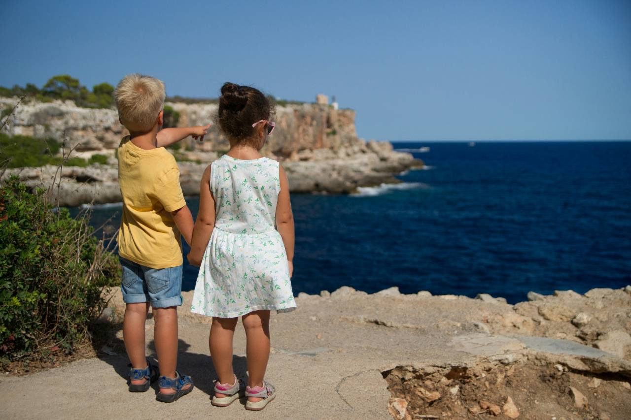 a photo of two children looking at the sea