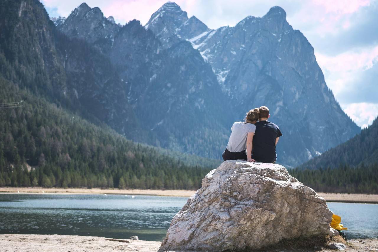 a photo of a couple sitting close together on a large rock