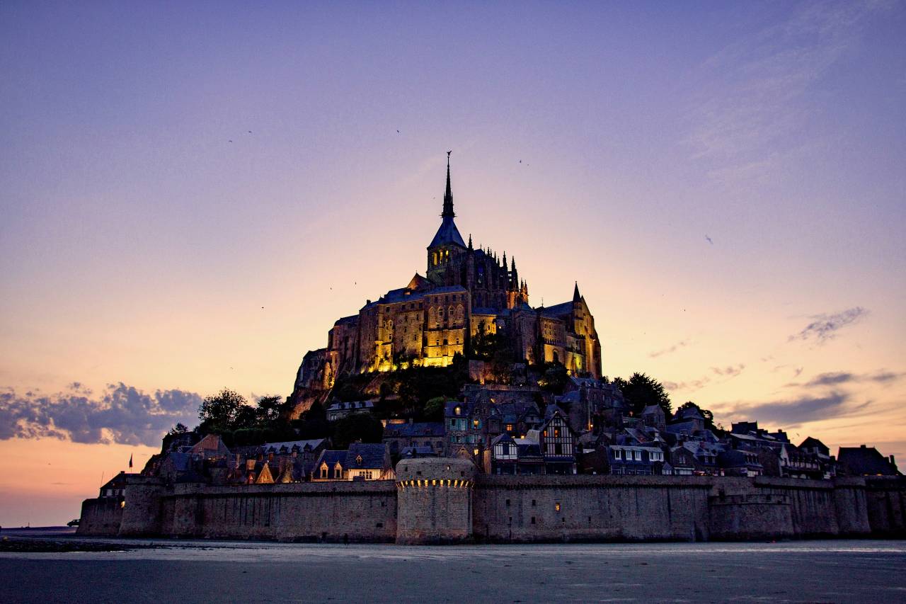 a castle with a high spire in the center, at late dusk