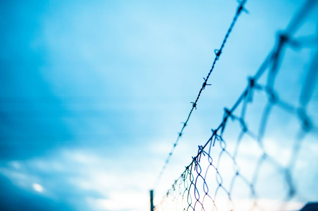 barbed wire in the foreground against a blue sky