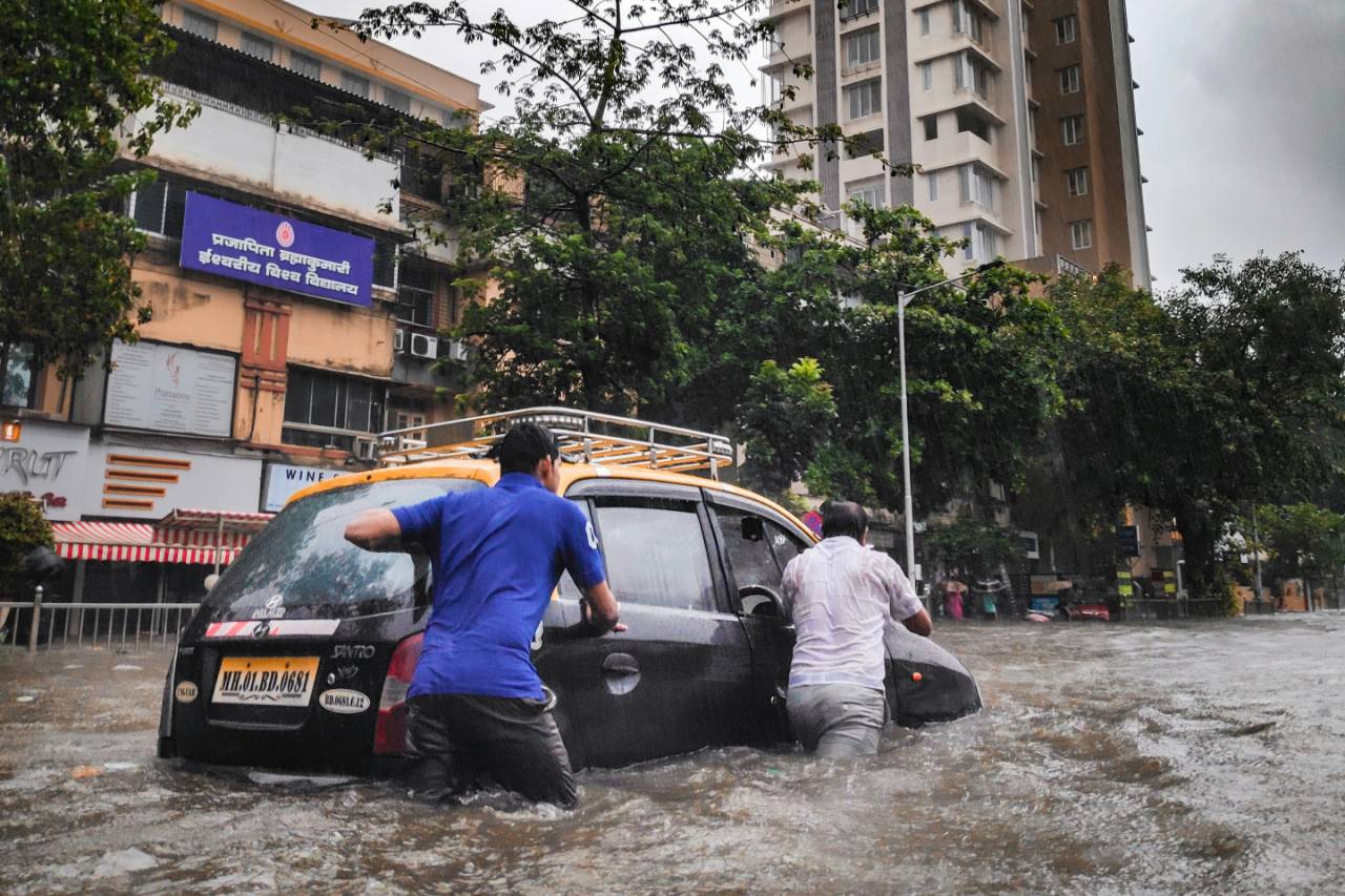 people pushing a car in a flood