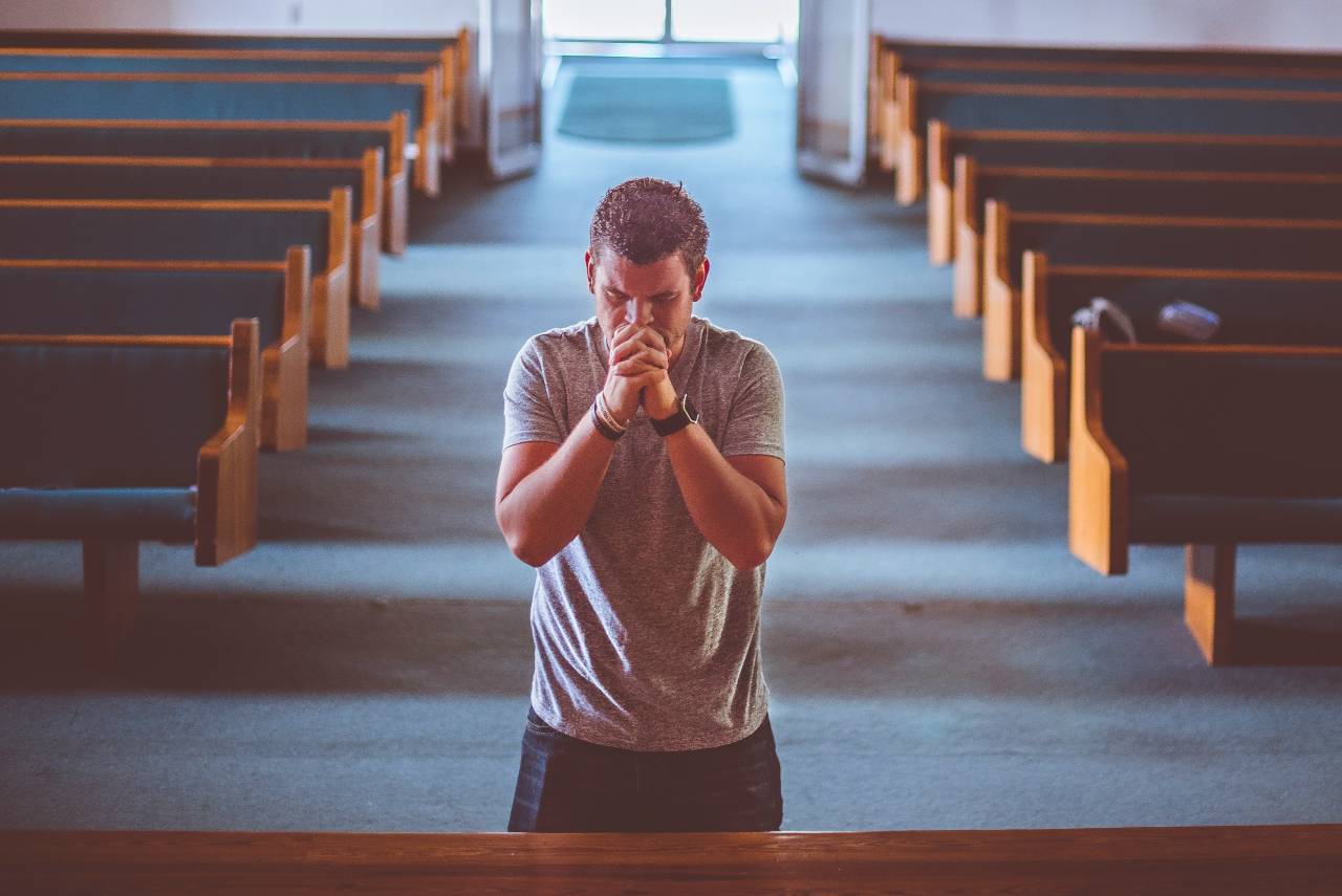 a man praying in an ejpty church
