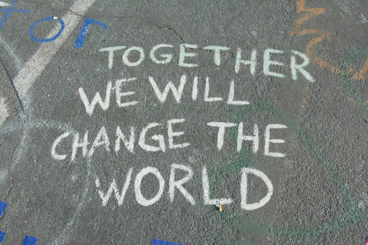Chalk on the pavement reads: Together we will change the world