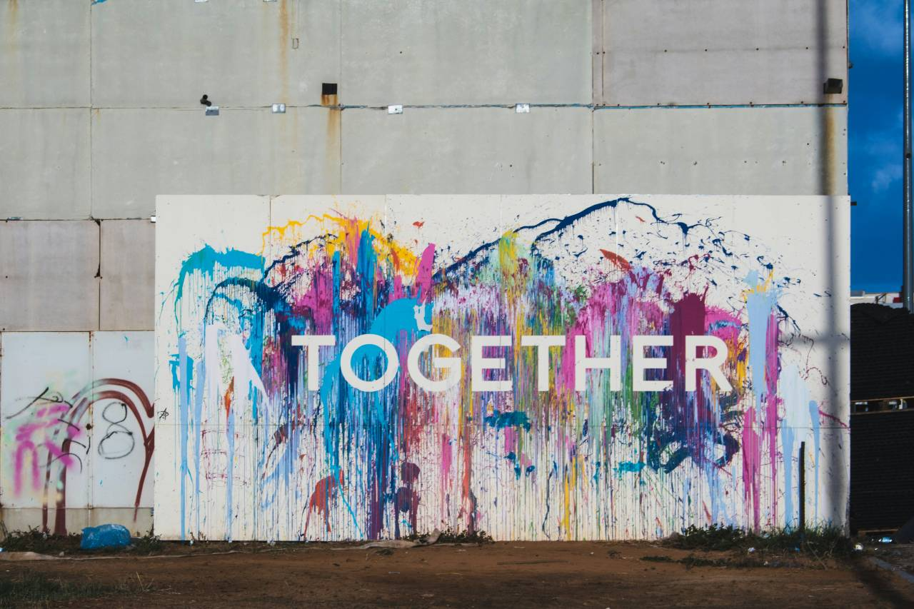 a wall, painted in may colors, reads: "together"