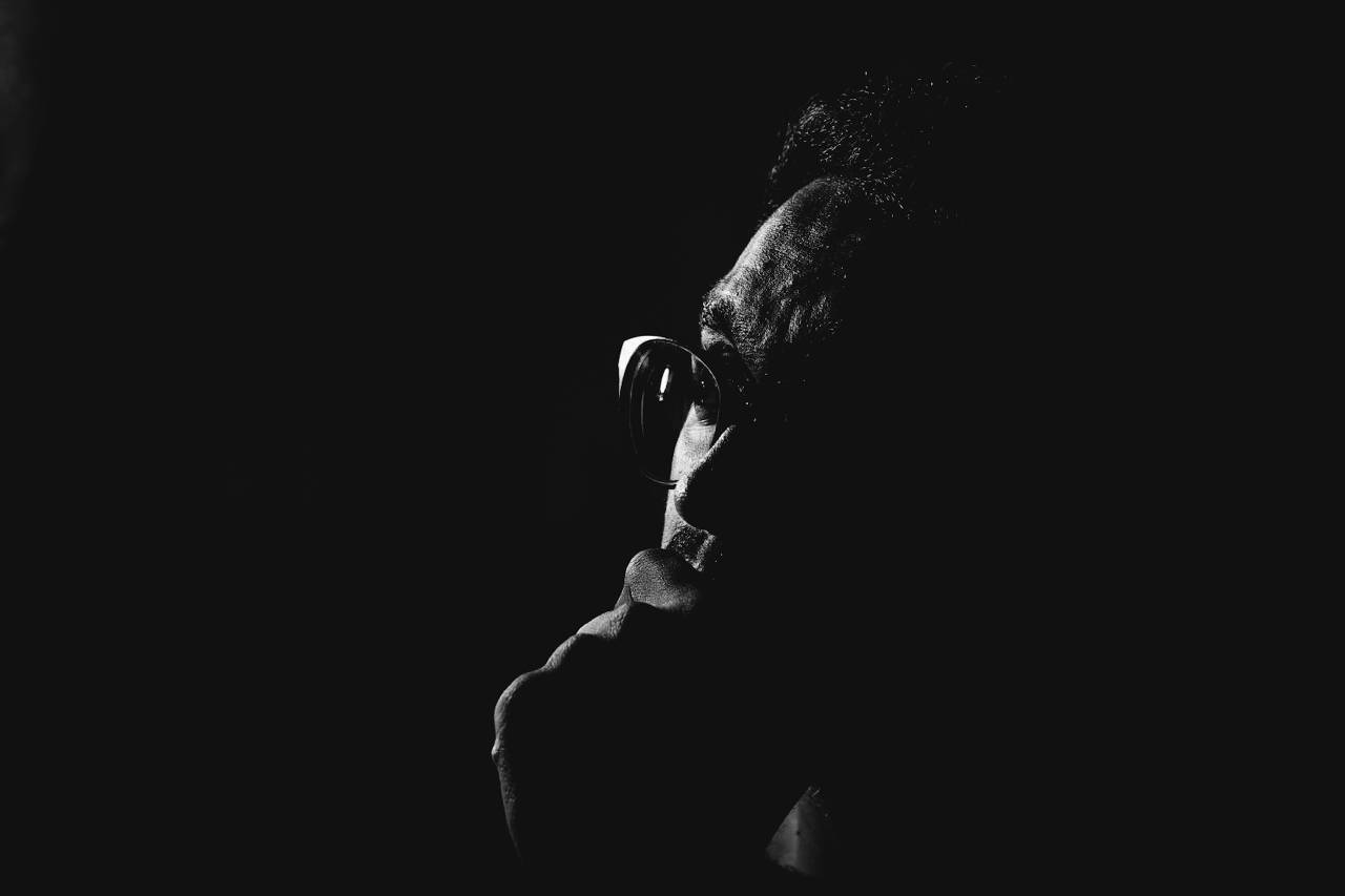 a man in the dark, hand to his chin