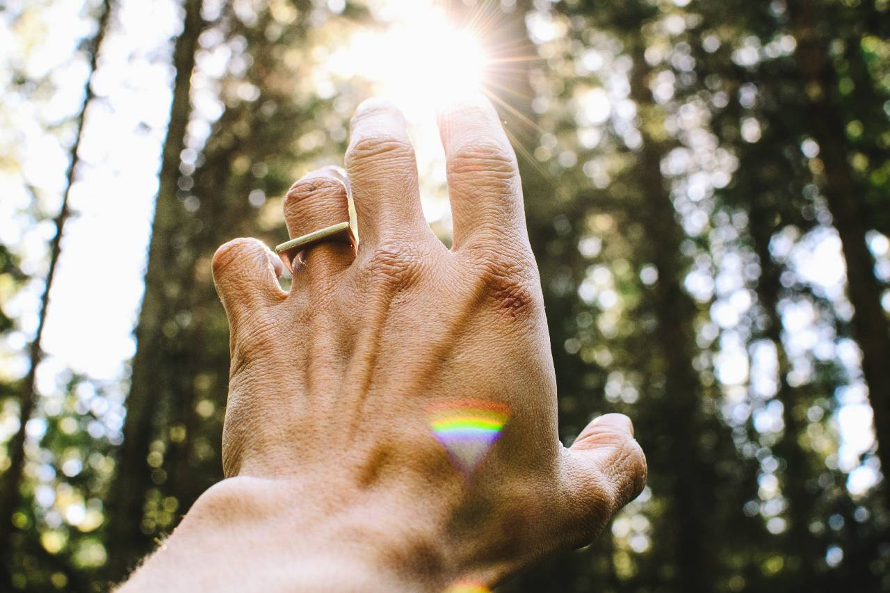 a hand reaching up toward the sun