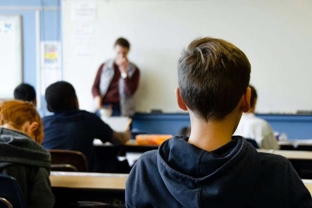 boy in black hoodie, teacher at front of room — symbol of messiah