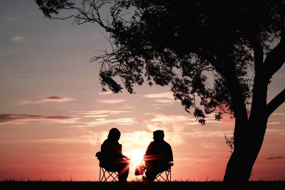 two people talking in front of a sunset