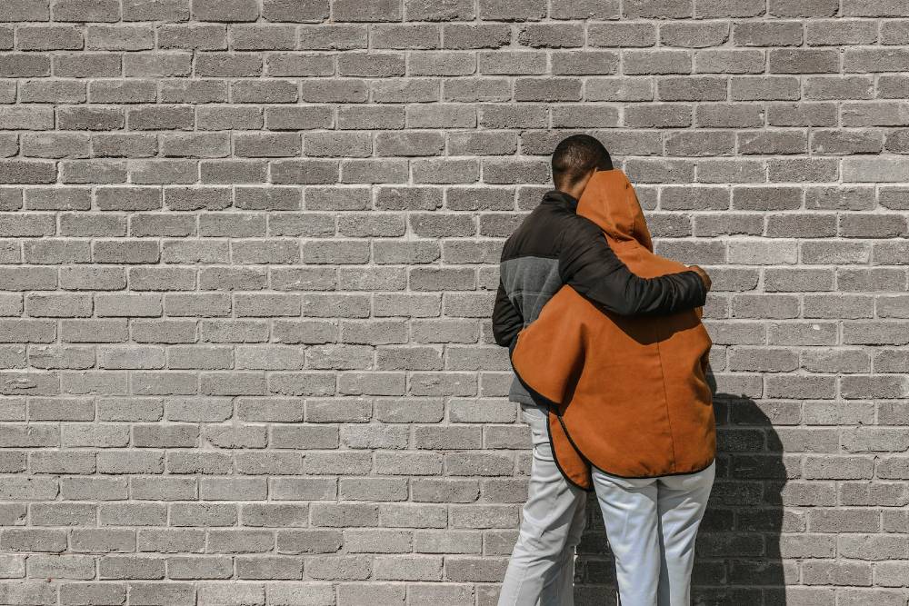 person holding another person in front of a wall